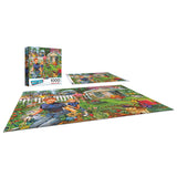 The ROSEART-BACK TO THE PAST-GARDENING WITH MOM 1000 piece jigsaw puzzle shows a vibrant garden, a man holding a cat, flowers, a white fence, and a house—ideal for family fun or as a gift for mom. Puzzle box is displayed alongside the completed image.