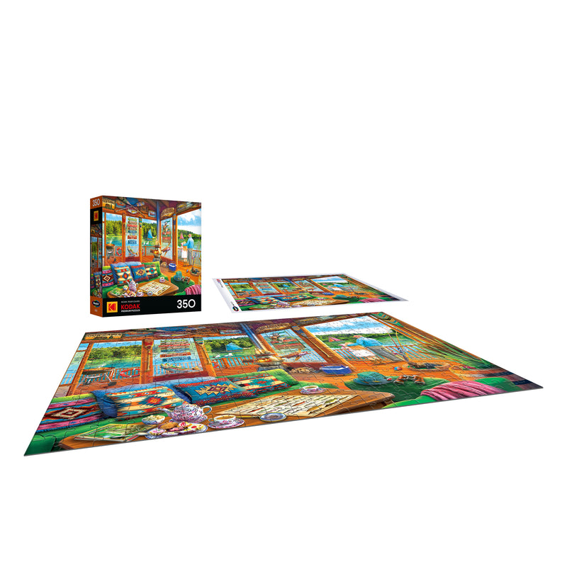 The ROSEART-KODAK PREMIUM-THE LAKE HOUSE-350 Piece Jigsaw Puzzle is displayed fully assembled, partially completed, and in its box, depicting a vibrant art scene.