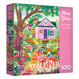 The ROSEART-OLIVIA GIBBS-FLORAL GARDEN-300 PIECE JIGSAW PUZZLE features a vibrant illustration of a pink house, outdoor table and chairs, and colorful flowers in a lively garden scene.