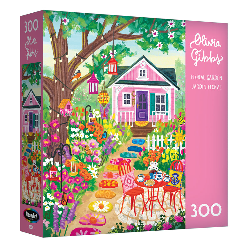 The ROSEART-OLIVIA GIBBS-FLORAL GARDEN-300 PIECE JIGSAW PUZZLE features a vibrant illustration of a pink house, outdoor table and chairs, and colorful flowers in a lively garden scene.