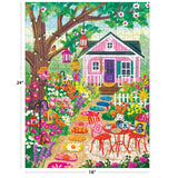 The ROSEART-OLIVIA GIBBS-FLORAL GARDEN 300 piece jigsaw puzzle features a colorful scene with a pink house, flowers, lanterns, a tree, and patio furniture. Finished size is 24 x 18 inches.