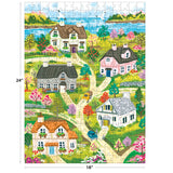 Vibrant illustration of the ROSEART-OLIVIA GIBBS-COASTAL COTTAGE TOWN 300 piece jigsaw puzzle, showing houses, gardens, cars, trees, winding paths & a distant lake. Puzzle size: 24" x 18".