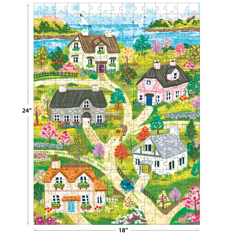 Vibrant illustration of the ROSEART-OLIVIA GIBBS-COASTAL COTTAGE TOWN 300 piece jigsaw puzzle, showing houses, gardens, cars, trees, winding paths & a distant lake. Puzzle size: 24" x 18".