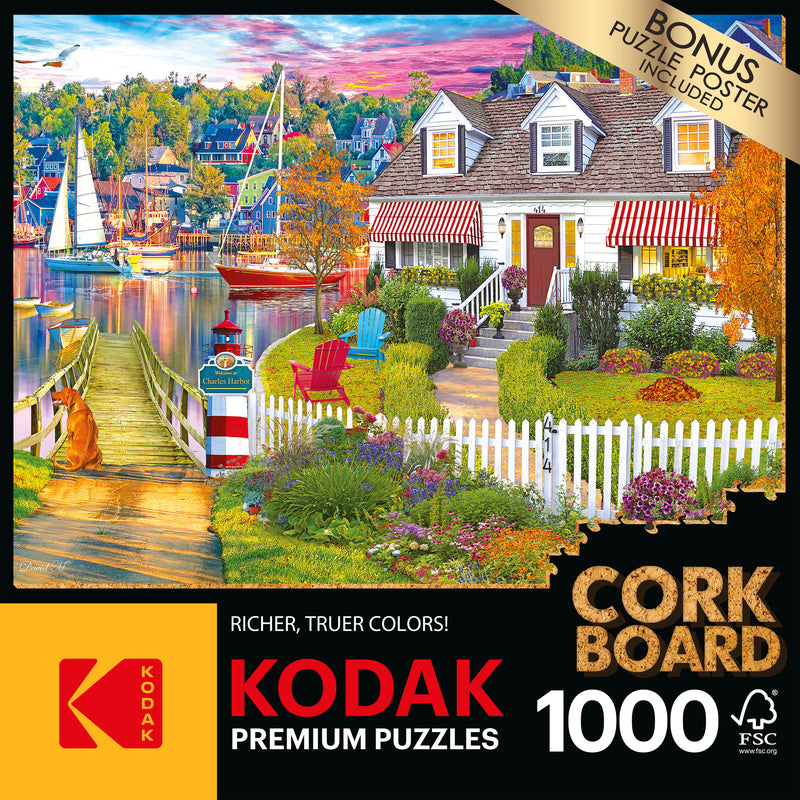 A RoseArt - Kodak Cork - Charles Harbor - 1000 Piece Jigsaw Puzzle box displaying a 1000-piece puzzle of a vibrant lakeside scene with a house, garden, sailboats, and colorful autumn trees. Text highlights "bonus puzzle poster included.
