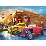 A colorful street scene features classic cars, including a yellow hot rod and a red convertible, parked outside "Clancy's" diner with an "Open 24 Hours" sign. A clock and an American flag are visible in the RoseArt - American Nostalgia - American Grill - 500 Piece Jigsaw Puzzle.