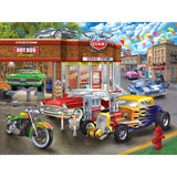 Illustration of a retro gas station with classic cars, motorcycles, and a hot rod garage. The scene includes vibrant vintage vehicles and colorful signage. RoseArt - American Nostalgia - Hot Rod Garage - 550 Piece Jigsaw Puzzle