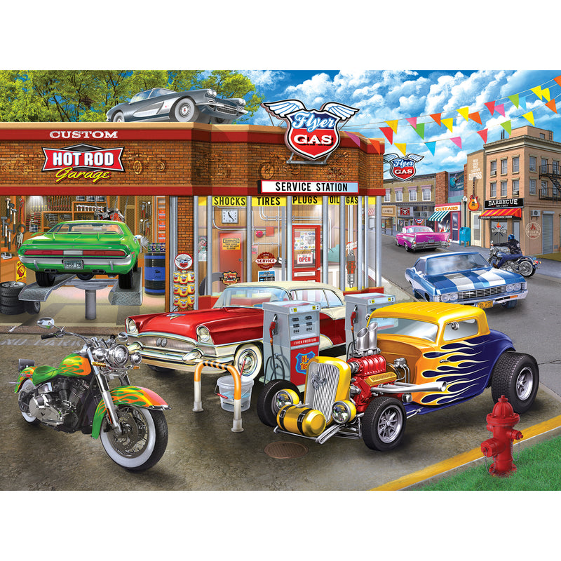 Illustration of a retro gas station with classic cars, motorcycles, and a hot rod garage. The scene includes vibrant vintage vehicles and colorful signage. RoseArt - American Nostalgia - Hot Rod Garage - 550 Piece Jigsaw Puzzle
