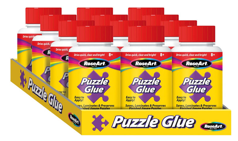 A display tray filled with ten bottles of RoseArt - Puzzle Glue - 4.5 ozs, each with a red cap. The packaging states it dries quick, clear, and bright, and is suitable for ages 8 and up.
