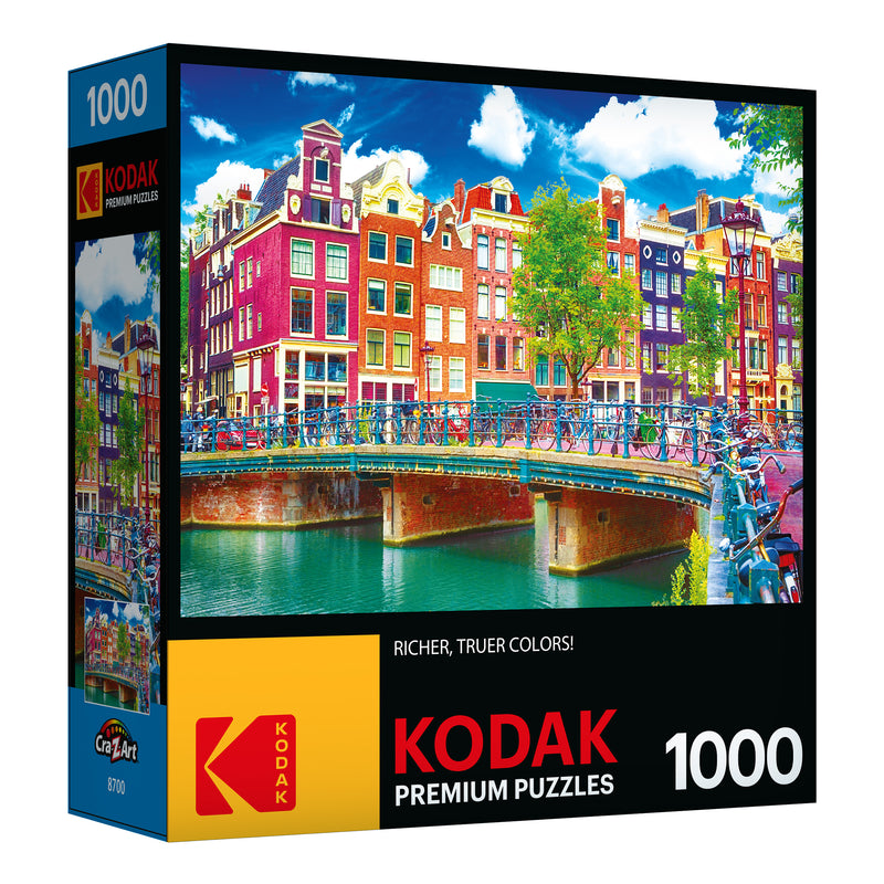 Box of a RoseArt - Kodak Premium - Colorful Waterfront Buildings, Amsterdam - 1000 Piece Jigsaw Puzzle set with 1000 pieces, featuring a colorful image of a canal with bicycles and vibrant buildings in the background.
