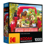 Box of a RoseArt - Kodak Premium - Stowaways - 1000 Piece Jigsaw Puzzle featuring an image of puppies sitting on the back of a red truck with flowers and produce. The puzzle has 1000 pieces and showcases rich, true colors.
