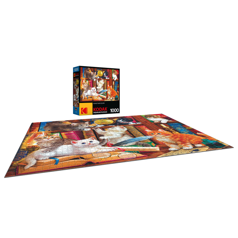 A completed RoseArt - Kodak Premium - Library Mischief - 1000 Piece Jigsaw Puzzle featuring various cats in a cozy room, with the puzzle box standing upright in the background. The puzzle box indicates it has 1000 pieces.
