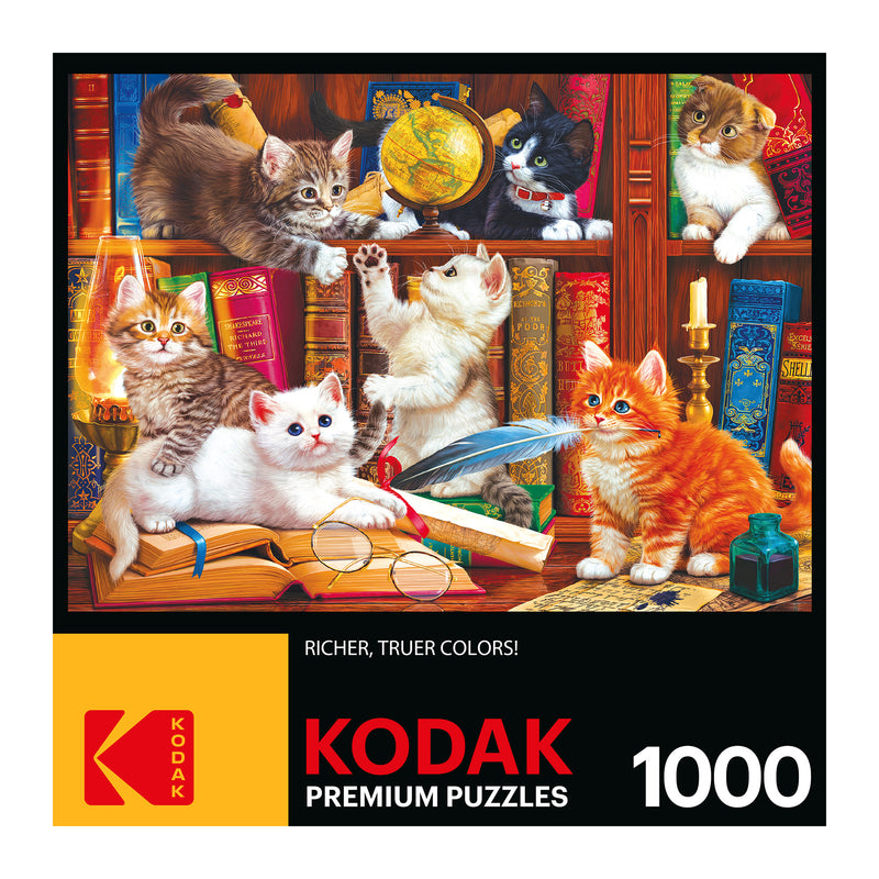 A RoseArt - Kodak Premium - Library Mischief - 1000 Piece Jigsaw Puzzle features an image of six cats interacting in front of bookshelves with various objects including a globe and a candle. The box emphasizes "Richer, Truer Colors!".