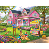 The ROSEART - BIGELOW ILLUSTRATIONS - LEMONADE ON THE LAWN - 500 PIECE JIGSAW PUZZLE showcases a pink house surrounded by flowers, with joyful adults and children at a lemonade stand, kids on the grass, and a charming scene perfect for both young and old.
