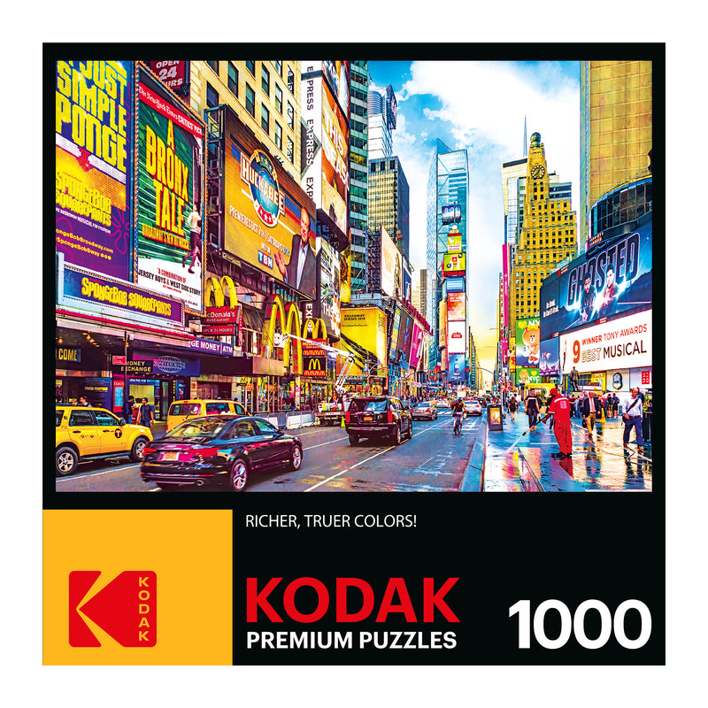 A colorful image of Times Square in New York City, featuring vibrant billboards, busy streets, and numerous pedestrians, on the box cover of a RoseArt - Kodak Premium - Times Square & 7th Avenue, Manhattan, NY - 1000 Piece Jigsaw Puzzle.