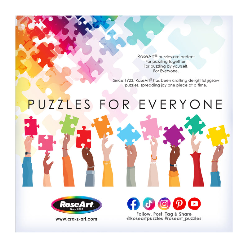 Hands of diverse skin tones hold colorful jigsaw pieces under "Puzzles for Everyone," featuring RoseArt branding and social media icons. Art by Millie Illustrates adds uniqueness to this inclusive image for the ROSEART - MILLIE ILLUSTRATES - MARSEILLE - 300 PIECE JIGSAW PUZZLE.