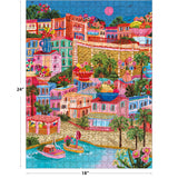 The ROSEART - MILLIE ILLUSTRATES - MARSEILLE 300-piece jigsaw puzzle features a vibrant tropical village scene with boats, colorful buildings, flowers, and palm trees, measuring 18x24 inches.