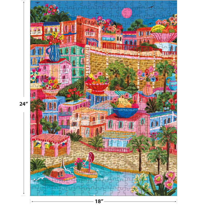 The ROSEART - MILLIE ILLUSTRATES - MARSEILLE 300-piece jigsaw puzzle features a vibrant tropical village scene with boats, colorful buildings, flowers, and palm trees, measuring 18x24 inches.