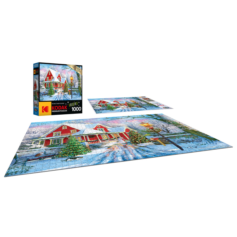 A completed RoseArt - Kodak Premium - Christmas at Home - 1000 Piece Jigsaw Puzzle depicting a snowy scene with a red house and Christmas decorations. The puzzle box is also shown with the same image.