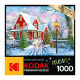 A colorful snowy holiday scene featuring a red house, decorated trees, a streetlamp, snow-covered yard, and a sleigh. The box states "RoseArt - Kodak Premium - Christmas at Home - 1000 Piece Jigsaw Puzzle.