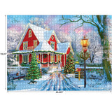 A completed RoseArt - Kodak Premium - Christmas at Home - 1000 Piece Jigsaw Puzzle depicting a snowy winter scene with a red house adorned with Christmas decorations, featuring a lit lamppost, evergreen trees, and a bench. Dimensions are 19.25" by 26.625".