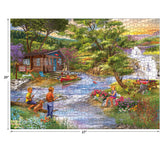 A completed RoseArt - Chris Bigelow - Fishing from the Banks - 1000 Piece Jigsaw Puzzle depicting a tranquil scene with children playing and fishing by a stream near a cottage, surrounded by trees and flowers. The puzzle measures 20 inches by 27 inches.
