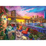 Colorful illustration of a balcony view with the Brooklyn Bridge, boats on the water, vibrant floral decorations, and a city skyline at sunset. A yellow dog naps on the deck amid patio furniture. RoseArt - Kodak Cork - Manhattan Balcony Sunset - 1000 Piece Jigsaw Puzzle.