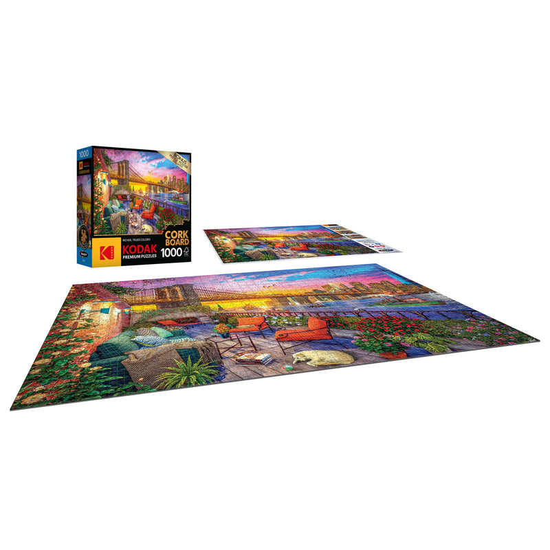 A completed 1000-piece RoseArt - Kodak Cork - Manhattan Balcony Sunset - 1000 Piece Jigsaw Puzzle is shown next to its box.