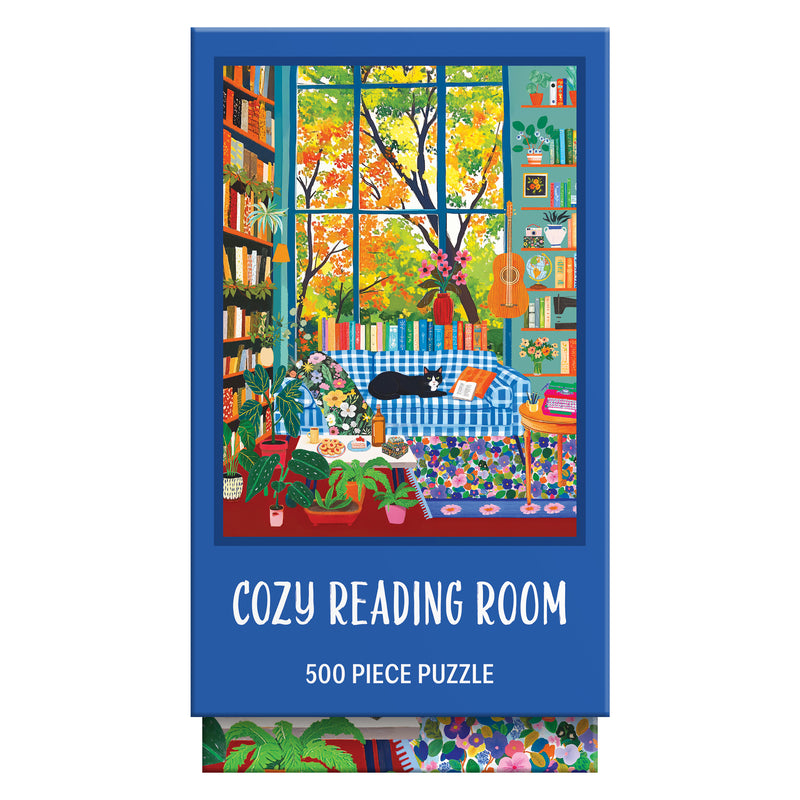 The ROSEART VERTICAL VISIONS Cozy Reading Room 500 Piece Jigsaw Puzzle features a cozy reading room with plants, bookshelves, a big window, blue sofa, and black cat. Text on the box: "Cozy Reading Room, 500 Piece Puzzle.