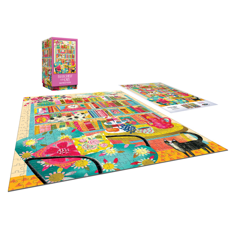 The ROSEART - VERTICAL VISIONS - Bookshelf with Cats 500 piece jigsaw puzzle features a cozy room scene with bookshelves, flowers, a chair, and black cats; includes the puzzle box and reference image.