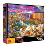 Box for a RoseArt - Kodak Premium - La Vida Las Vegas - 3000 Piece Jigsaw Puzzle featuring a colorful, detailed image of a Las Vegas skyline with a table of food in the foreground.