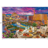 A completed RoseArt - Kodak Premium - La Vida Las Vegas - 3000 Piece Jigsaw Puzzle depicts a vibrant view of a cityscape with tall buildings, fountains, and a rooftop dining setup in the foreground during sunset.