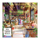 A cozy cafe with customers enjoying food and drinks. The interior features plants, hanging lights, and large windows. The scene is portrayed on the packaging of the "RoseArt - My Happy Place - The Neighborhood Cafe - 750 Piece Jigsaw Puzzle.