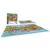 A completed RoseArt - Home Country - The Americana - 1000 Piece Jigsaw Puzzle depicting a colorful village scene is displayed with its box.