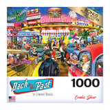 A vibrant puzzle box cover shows a lively 1950s diner scene with cars, people, and neon lights, titled RoseArt - Back to the Past - Cookie's Diner - 1000 Piece Jigsaw Puzzle by Edward Wargo.