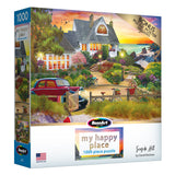 A 1000-piece puzzle box featuring a colorful seaside house and garden scene titled "RoseArt - My Happy Place - Seaside Hill - 1000 piece jigsaw puzzle" by David Maclean, with a bonus puzzle poster included.