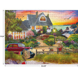 The RoseArt - My Happy Place - Seaside Hill - 1000 piece jigsaw puzzle depicts a coastal house with a garden at sunset. A red car, bicycles, and a wheelbarrow with flowers are in the foreground. Dimensions are 19.25 by 26.625 inches.