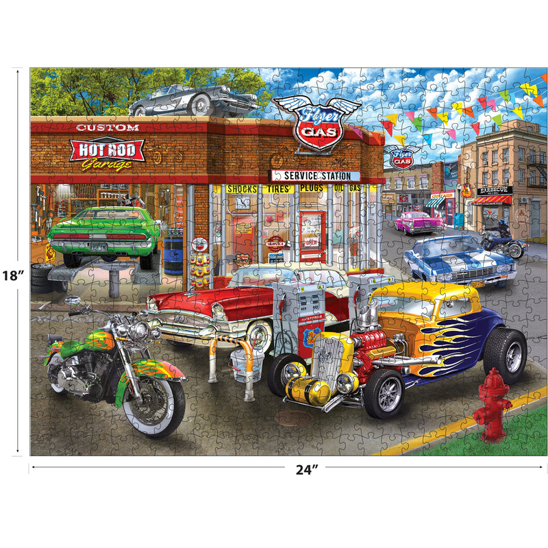 A completed RoseArt - American Nostalgia - Hot Rod Garage - 550 Piece Jigsaw Puzzle featuring a vintage service station with a variety of classic cars and a motorcycle parked in front. The puzzle dimensions are 18 inches by 24 inches.