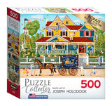 Image of a RoseArt - Puzzle Collector - Painted Lady - 500 Piece Jigsaw Puzzle box featuring colorful Victorian-style houses painted by Joseph Holodook. The box includes a bonus puzzle poster and is branded "Puzzle Collector".