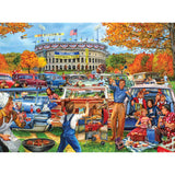 A lively tailgate party is depicted outside a stadium with people cooking, eating, and playing games near vintage cars. The marquee on the stadium reads, "Welcome Football Fans," captured perfectly in the RoseArt - Back to the Past - Tailgating Fun - 1000 Piece Jigsaw Puzzle.