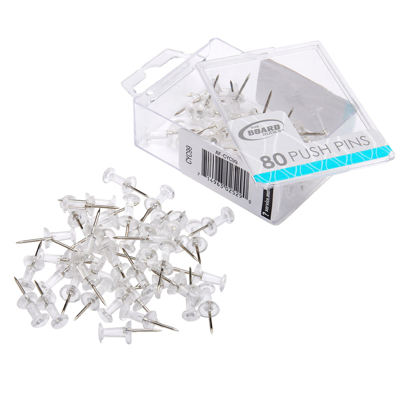 A clear plastic box labeled "Board Dudes PUSH PINS - Clear 80 Count" is open with several transparent push pins spilled out in front of it.
