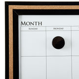 Close-up of a framed monthly Board Dudes Dry Erase Calendar Cork Magnetic Combo 22 x 18 inches: Stylish Organization for Any Space. The calendar shows columns for Sunday, Monday, and Tuesday. A black circular magnet is placed in the Monday column.