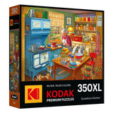 A 350-piece RoseArt - KODAK Premium - Grandma's Kitchen - 350 Piece Jigsaw Puzzle box showing an illustration of a colorful kitchen scene with an elderly woman baking, a dog nearby, and various cooking tools and ingredients around. Brand name and title included.
