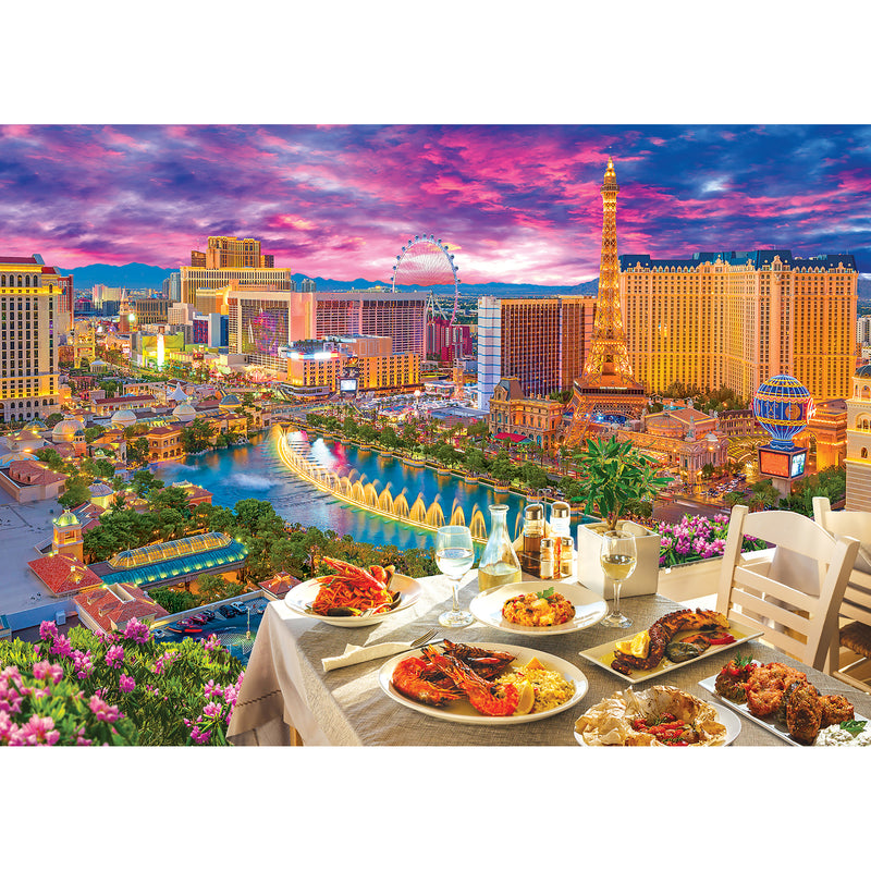 A RoseArt - Kodak Premium - La Vida Las Vegas - 3000 Piece Jigsaw Puzzle with various dishes and drinks overlooks a Las Vegas skyline at sunset, featuring hotels, casinos, and landmarks such as the Eiffel Tower replica and a Ferris wheel.