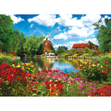 Scenic view of a windmill, house, and garden by a calm body of water, with vibrant flowers in the foreground and a blue sky with clouds overhead: RoseArt - Kodak Premium - Hunsett Mill and the River Ant, Norfolk, England - 1000 Piece Jigsaw Puzzle.