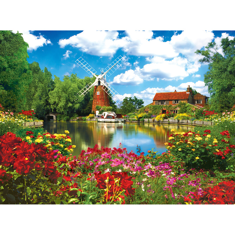 Scenic view of a windmill, house, and garden by a calm body of water, with vibrant flowers in the foreground and a blue sky with clouds overhead: RoseArt - Kodak Premium - Hunsett Mill and the River Ant, Norfolk, England - 1000 Piece Jigsaw Puzzle.