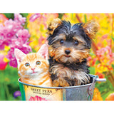 A small brown and black puppy and an orange and white kitten sit together inside a metal bucket labeled "Sweet Peas" amidst vibrant flowers in the RoseArt - Kodak Premium - Bucket Buddies - 100 Piece Jigsaw Puzzle.