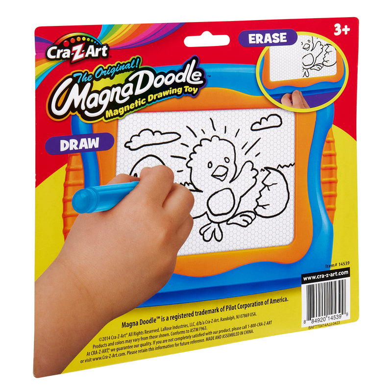 A hand drawing a bird on a Mini Magna Doodle magnetic drawing toy package. The package displays a cartoon bird image with the words "Draw" and "Erase" and is suitable for ages 3 and up.