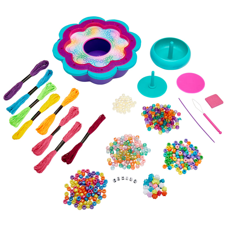 A Shimmer 'n Sparkle 2 in 1 Spin & Bead Bracelet Studio including various colored threads, an assortment of beads, a flower-shaped tray, and accessory tools.