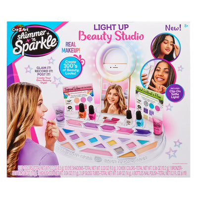 Product box of Shimmer 'n Sparkle Light Up Beauty Studio, showing makeup kit components, photographs of children using the set, and text highlighting features like real makeup and clip-on light.
