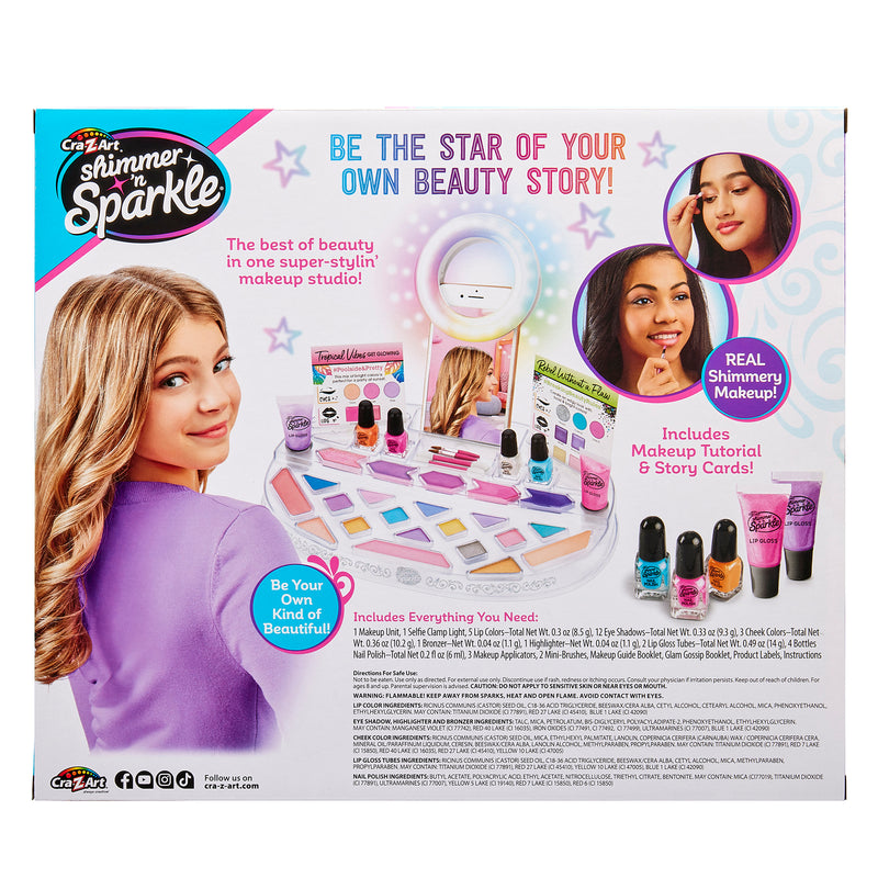 Box labeled "Shimmer 'n Sparkle Light Up Beauty Studio" showcasing a makeup studio toy set with accessories. Includes makeup products, tutorial, and story cards. Image of a smiling girl applying makeup on the right side.